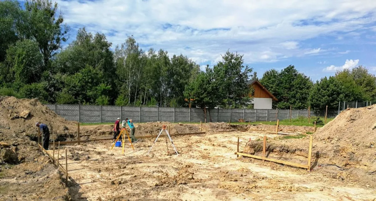 Wytyczanie ław fundamentowych przez geodetę na placu budowy — moment po uzyskaniu pozwolenia na budowę