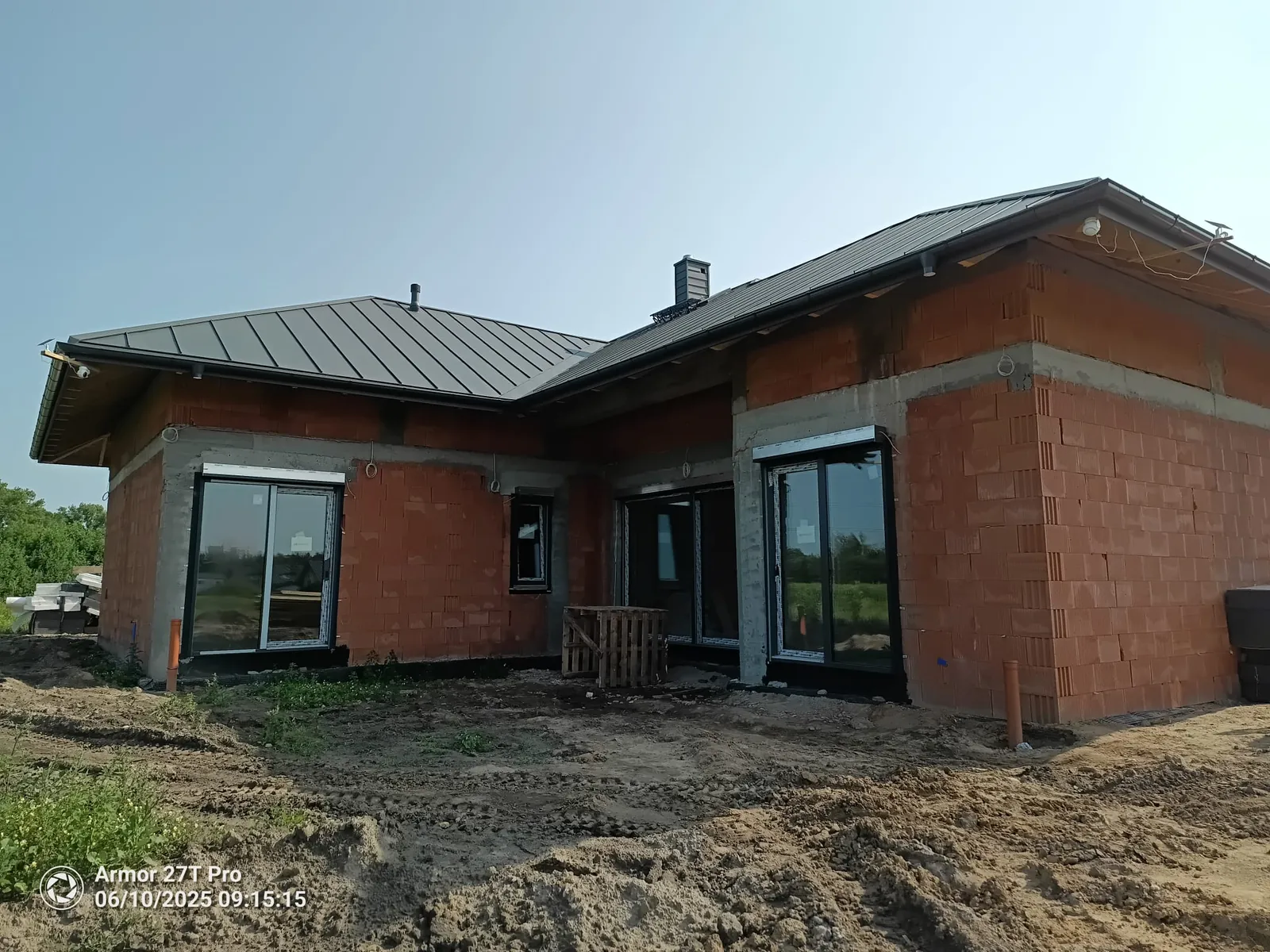 Dom w stanie surowym zamkniętym — front z oknami i dachem z blachy na rąbek